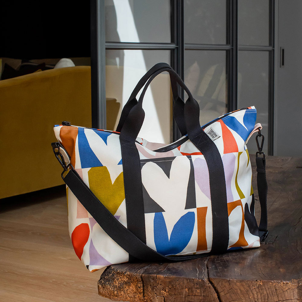 coated cotton canvas weekend bag with multicolour hearts design, black webbing grab handles and detachable shoulder strap 