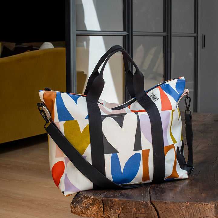 coated cotton canvas weekend bag with multicolour hearts design, black webbing grab handles and detachable shoulder strap 