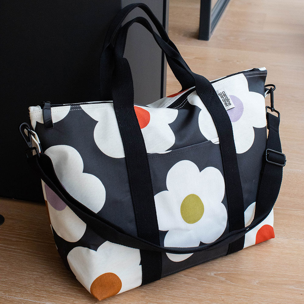 coated cotton canvas weekend bag with multi flower charcoal design, black webbing grab handles and detachable shoulder strap