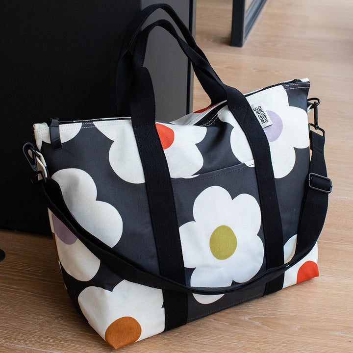 coated cotton canvas weekend bag with multi flower charcoal design, black webbing grab handles and detachable shoulder strap