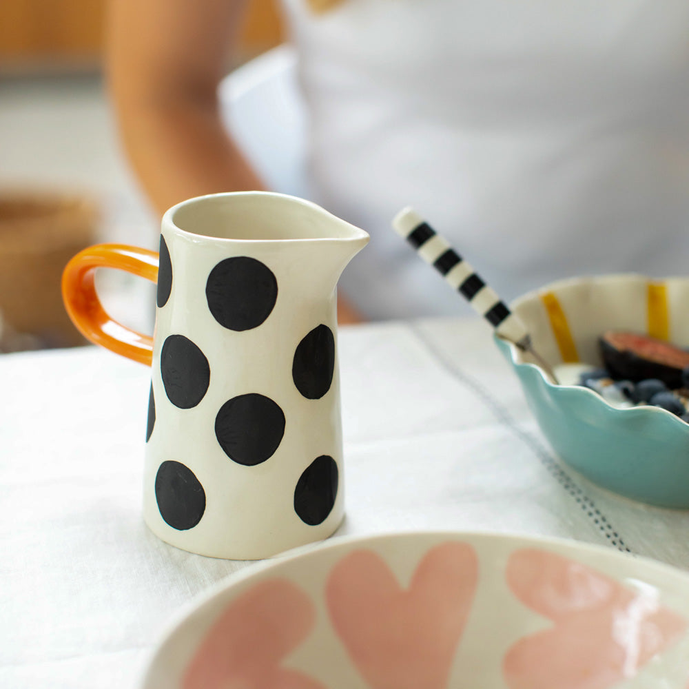 hand painted ceramic jug with big black spots design and orange elongated handle