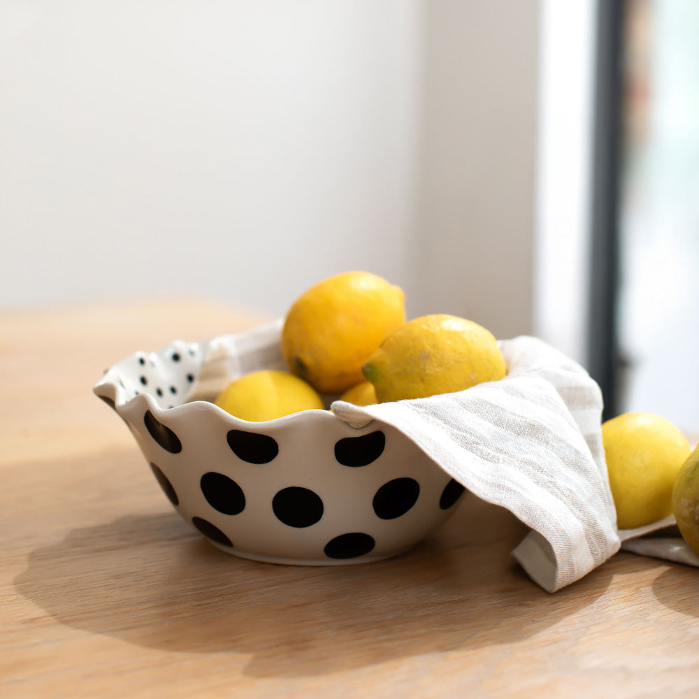 scallop edged ceramic bowl in white with big black spots on the outside and small black dots on the inside