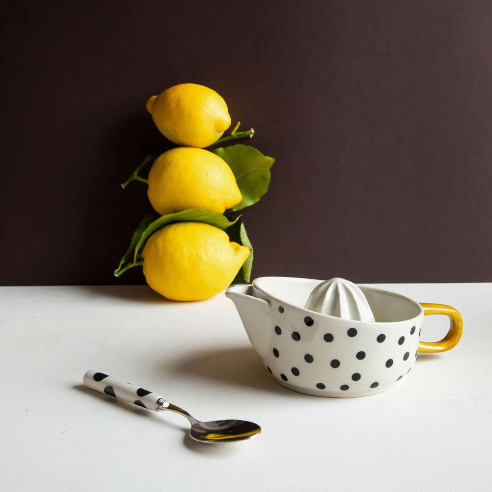 hand painted ceramic citrus squeezer with a small black dots design and mustard handle
