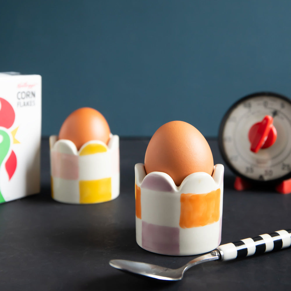 set of 2 hand painted stoneware egg cups in yellow/pink and orange/lilac check designs