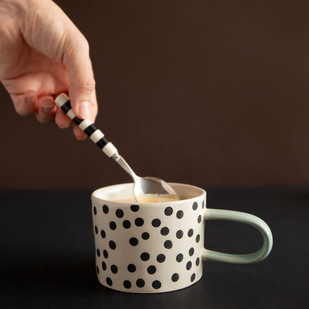 hand painted ceramic stoneware mug with small black dots design and a light blue elongated handle