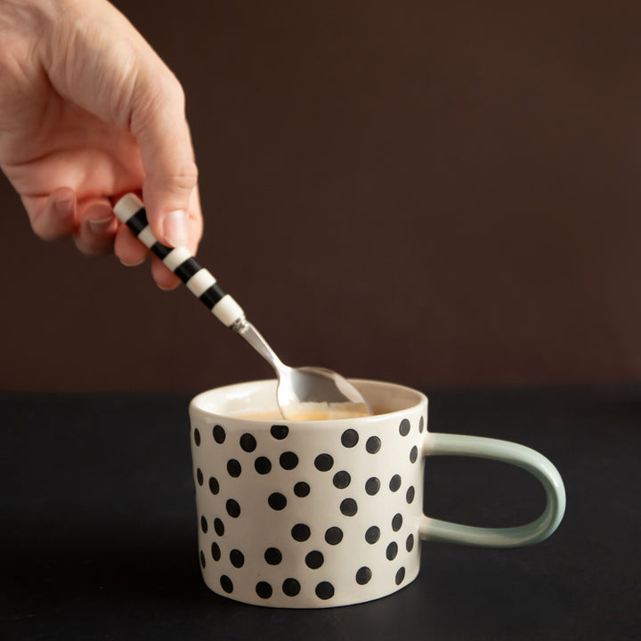 hand painted ceramic stoneware mug with small black dots design and a light blue elongated handle