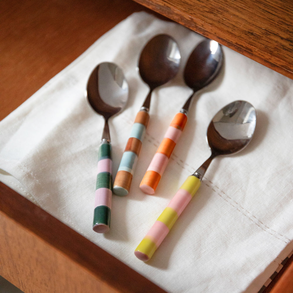 4 colourful striped ceramic & stainless steel teaspoons on a white napkin