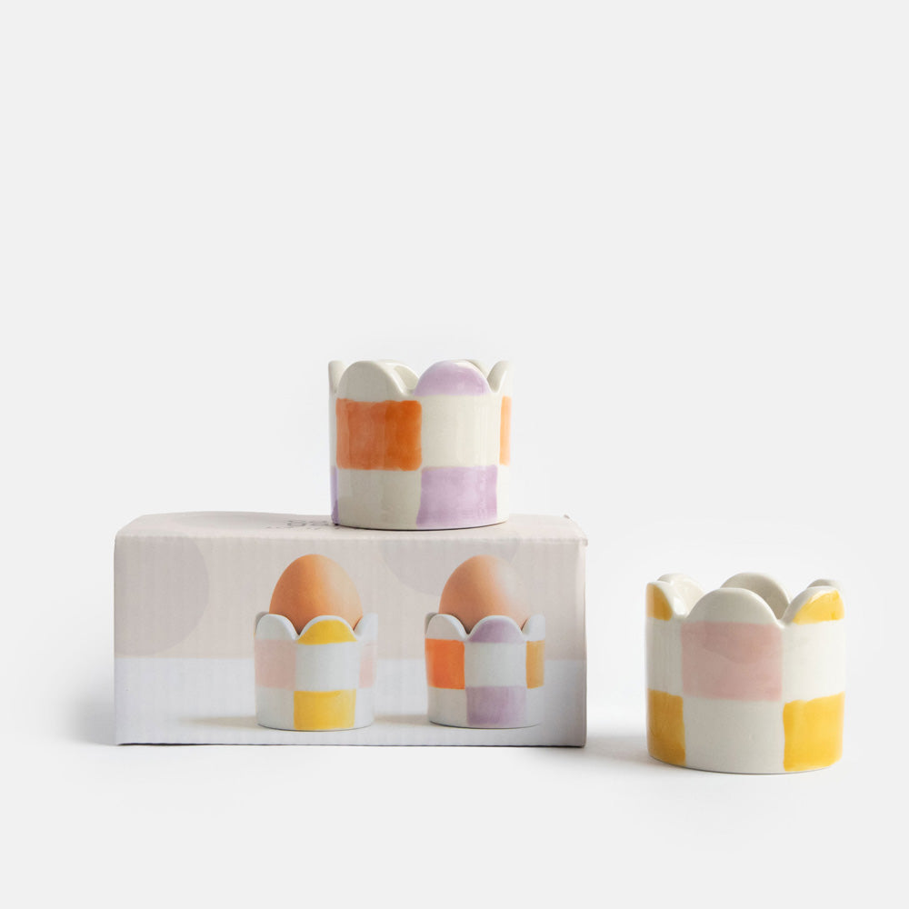set of 2 hand painted stoneware egg cups in yellow/pink and orange/lilac check designs