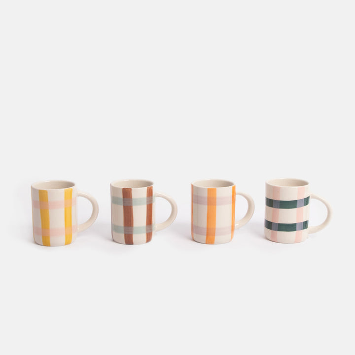 Set of four espresso cups with colourful checked patterns lined up on a white background