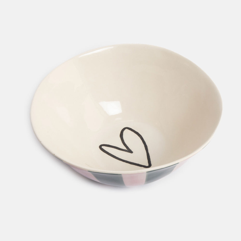 A ceramic bowl with a warm cream interior, featuring a simple black hand-drawn heart on the bottom and a pink, gray, and black patterned exterior, shown on a light gray background.