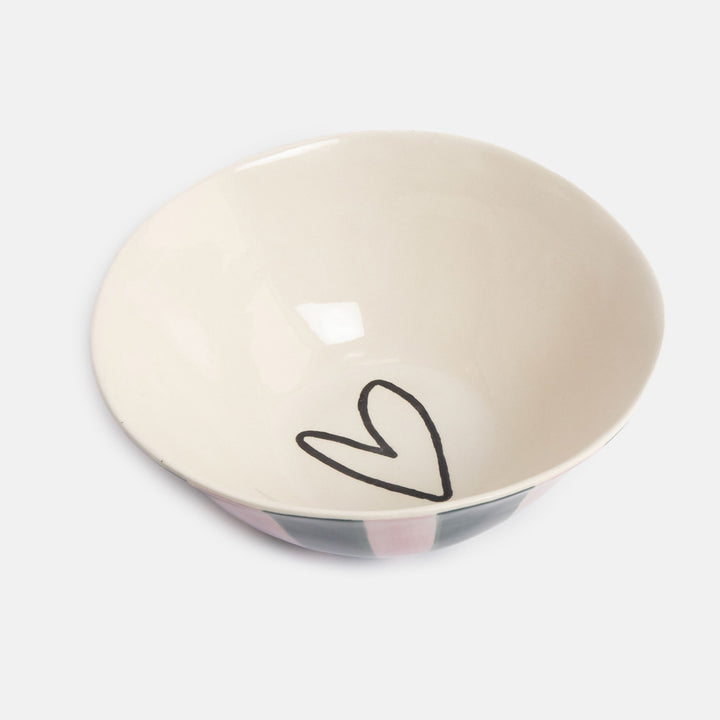 A ceramic bowl with a warm cream interior, featuring a simple black hand-drawn heart on the bottom and a pink, gray, and black patterned exterior, shown on a light gray background.