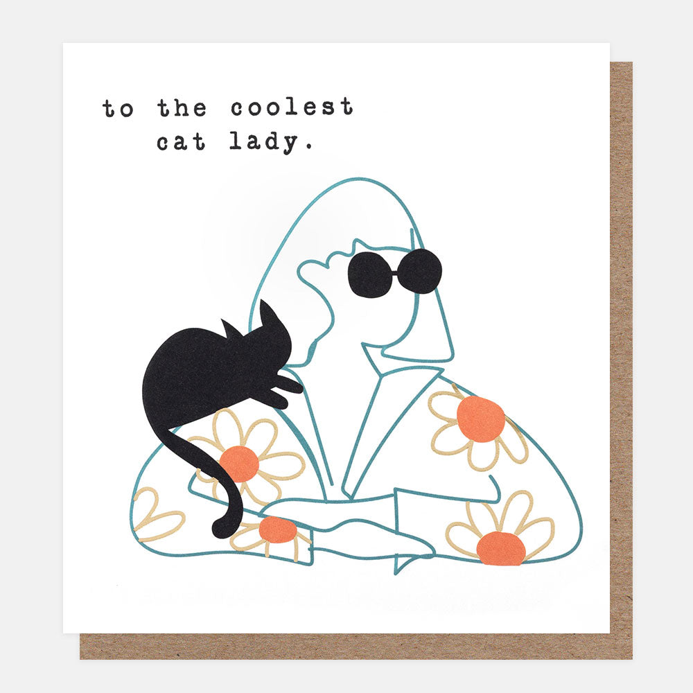A square white greeting card with a minimalist illustration of a woman in a black sunglasses and a flowery orange shirt with a black cat on her shoulder, with the text 'to the coolest cat lady'. A brown kraft envelope is partially visible behind the card.