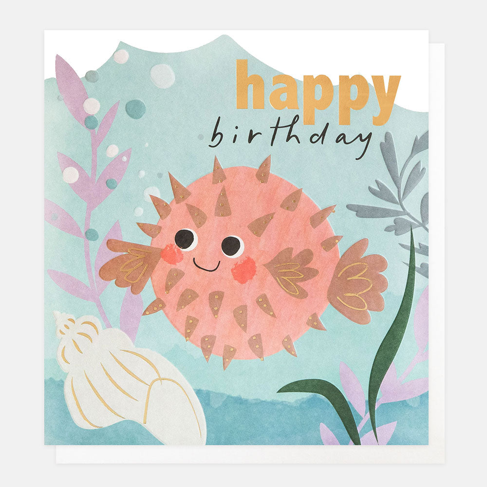 kid's birthday card featuring a pink smiling pufferfish with a shell and seaweed and 'happy birthday' text in gold