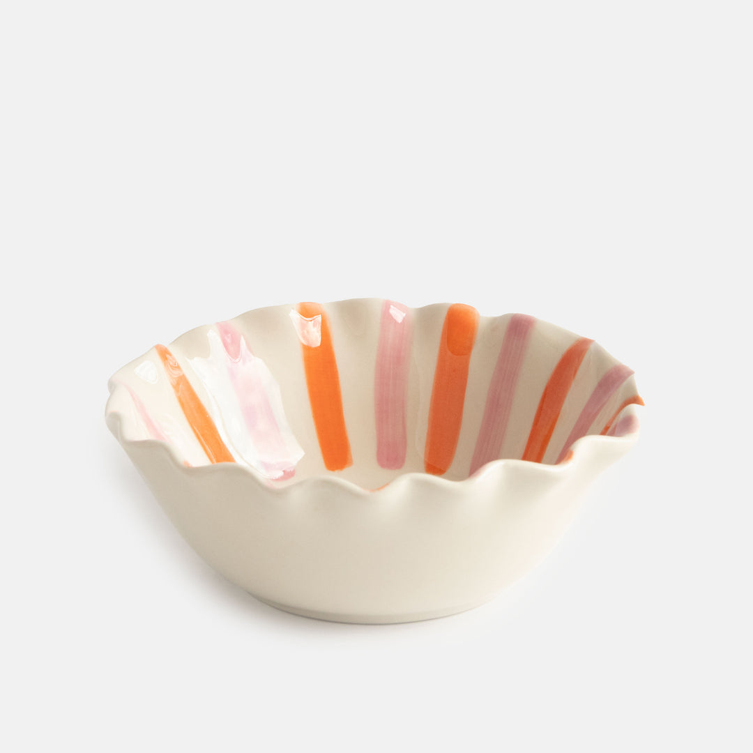 scalloped edge glazed stoneware cereal bowl with pink and orange stripes and black bow design inside