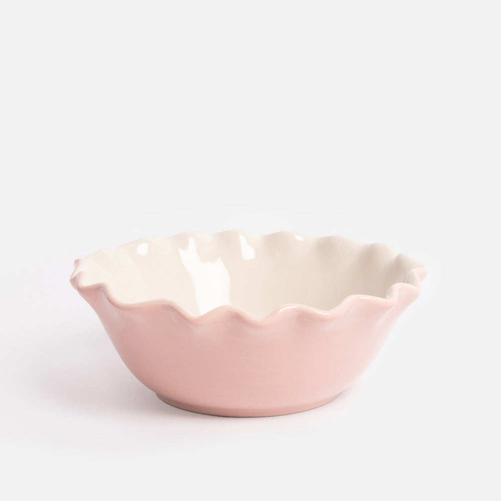 Pink ceramic bowl with scalloped edge on a white background