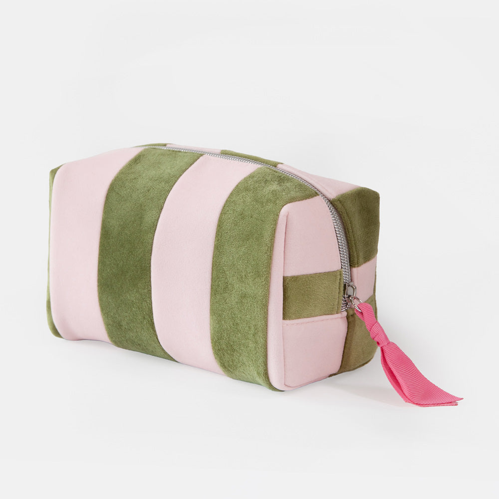 A rectangular zippered wash bag with alternating vertical stripes of dusty pink and olive green velvet, featuring a bright pink tassel zipper pull on a white background.