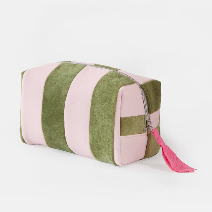 A rectangular zippered wash bag with alternating vertical stripes of dusty pink and olive green velvet, featuring a bright pink tassel zipper pull on a white background.