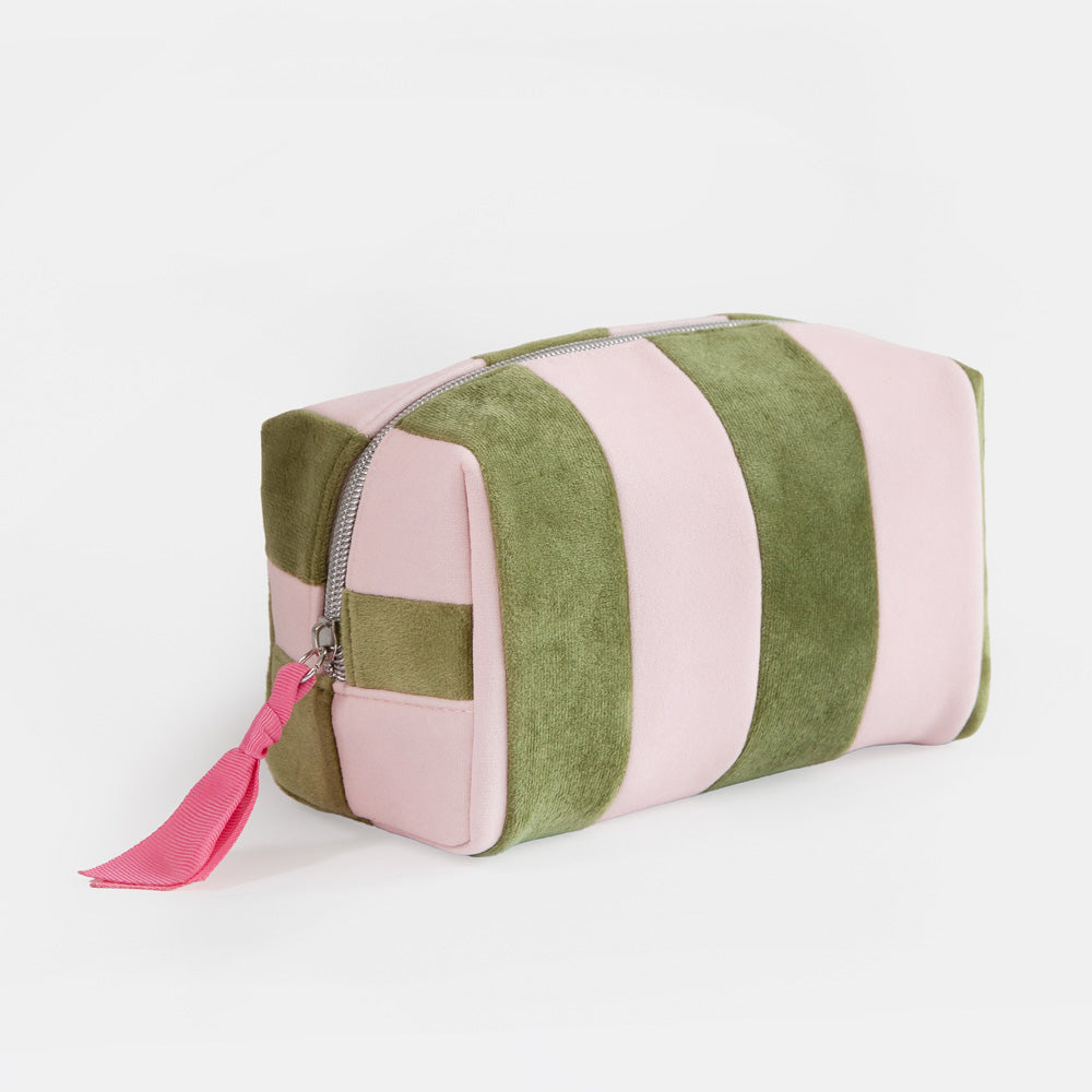 A rectangular zippered wash bag with alternating vertical stripes of dusty pink and olive green velvet, featuring a bright pink tassel zipper pull on a white background.