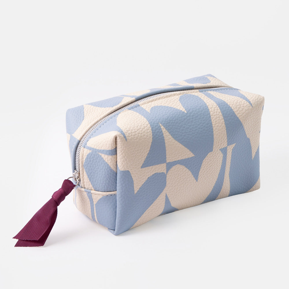 A rectangular zippered cosmetic pouch with a light blue and cream geometric pattern, featuring a dark purple tassel zipper pull, shown on a light gray background.