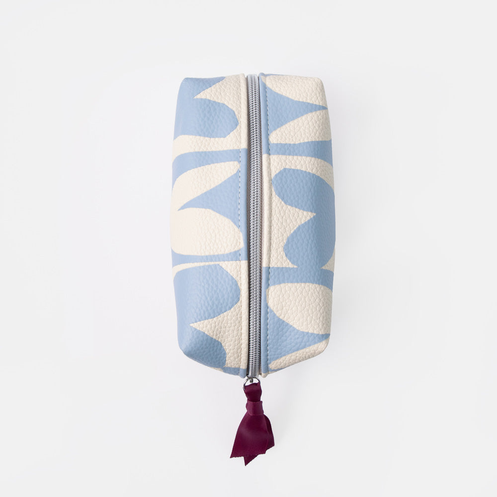 A rectangular zippered pouch with a light blue and cream abstract floral pattern, featuring a dark burgundy leather tassel pull on a silver zipper, set against a plain white background.