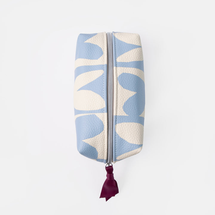 A rectangular zippered pouch with a light blue and cream abstract floral pattern, featuring a dark burgundy leather tassel pull on a silver zipper, set against a plain white background.