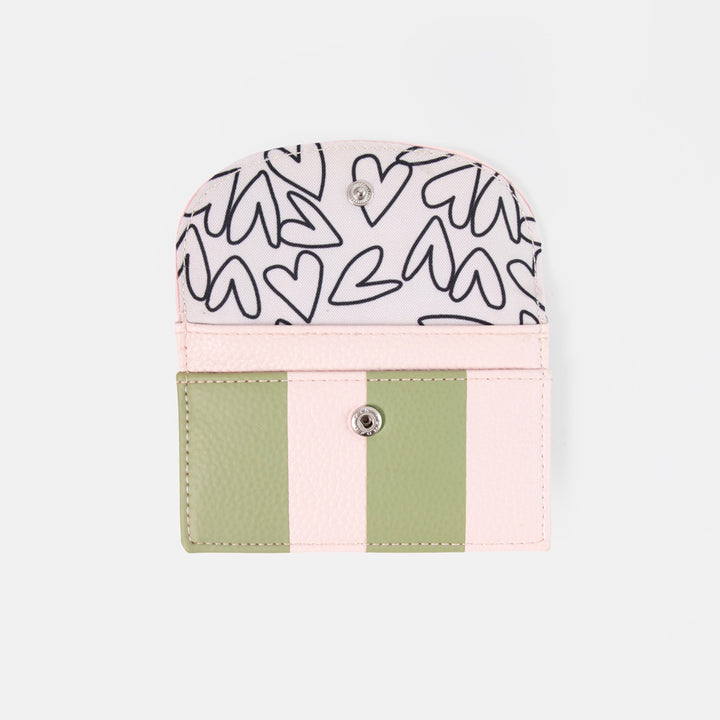 A small card holder or wallet with a light pink and sage green color-blocked design, featuring a white top flap with black heart line art pattern and a silver snap button closure, shown on a light gray background.