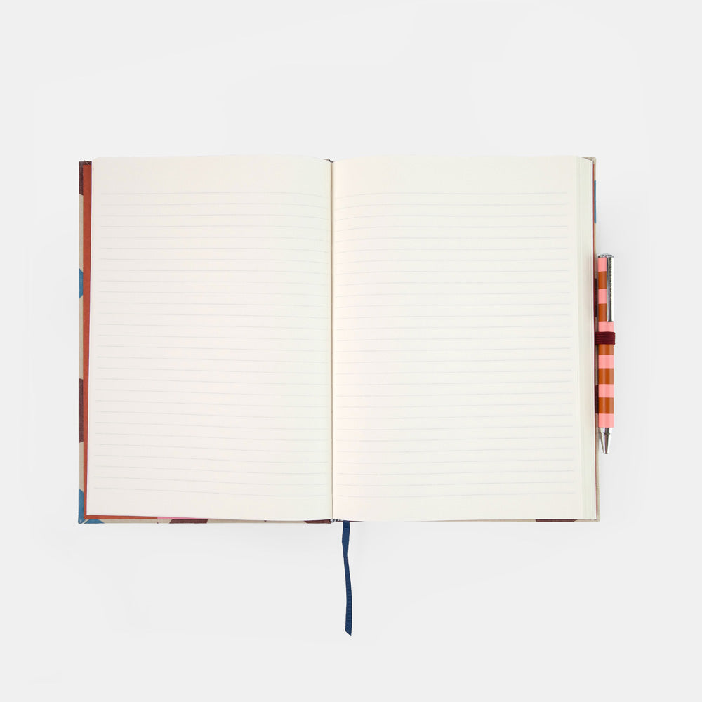 An open lined notebook with a colorful patterned cover and ribbon bookmark, shown on a light gray background with a striped pen tucked on the right side.