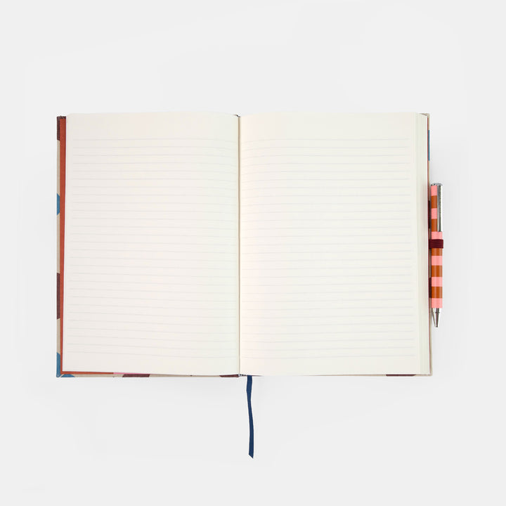 An open lined notebook with a colorful patterned cover and ribbon bookmark, shown on a light gray background with a striped pen tucked on the right side.