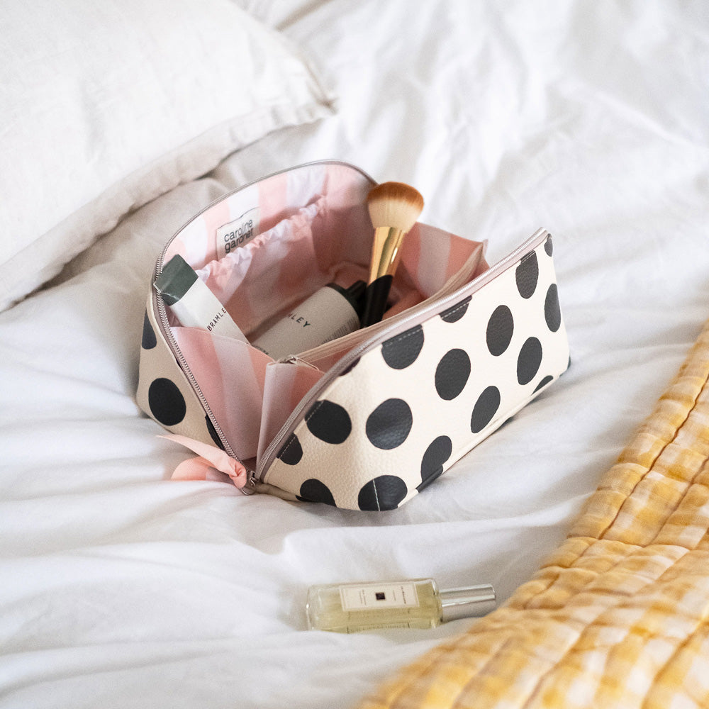 diagonal zip flat lay vegan leather wash bag in monochrome spots with top handle, silver zip and soft pink grosgrain pull