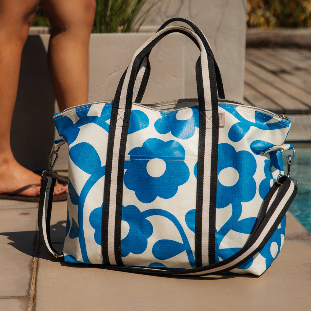 coated cotton canvas weekend bag with blue floral design and monochrome stripe webbing grab handles and detachable shoulder strap 
