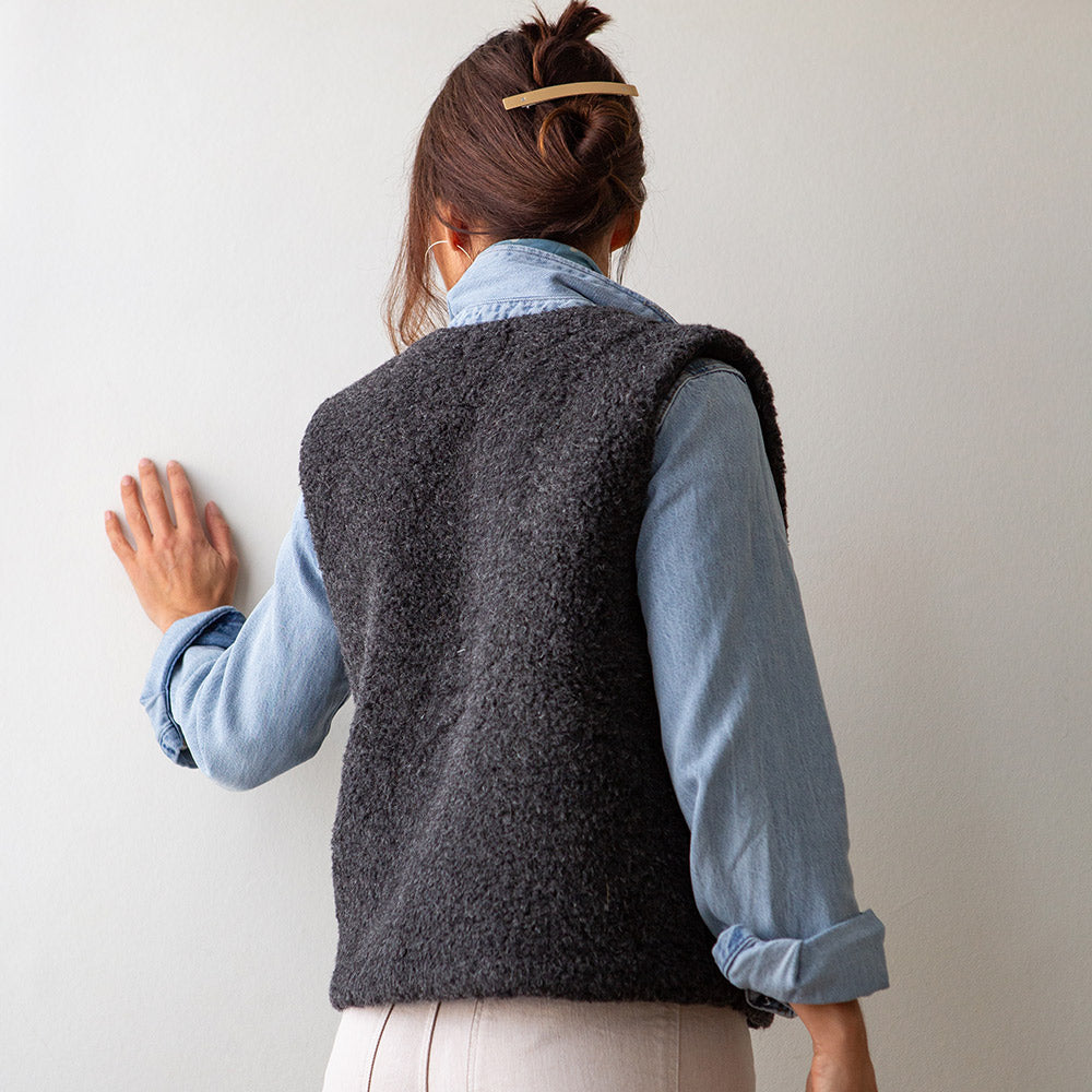 woman wearing a charcoal grey merino vest over a light wash denim shirt