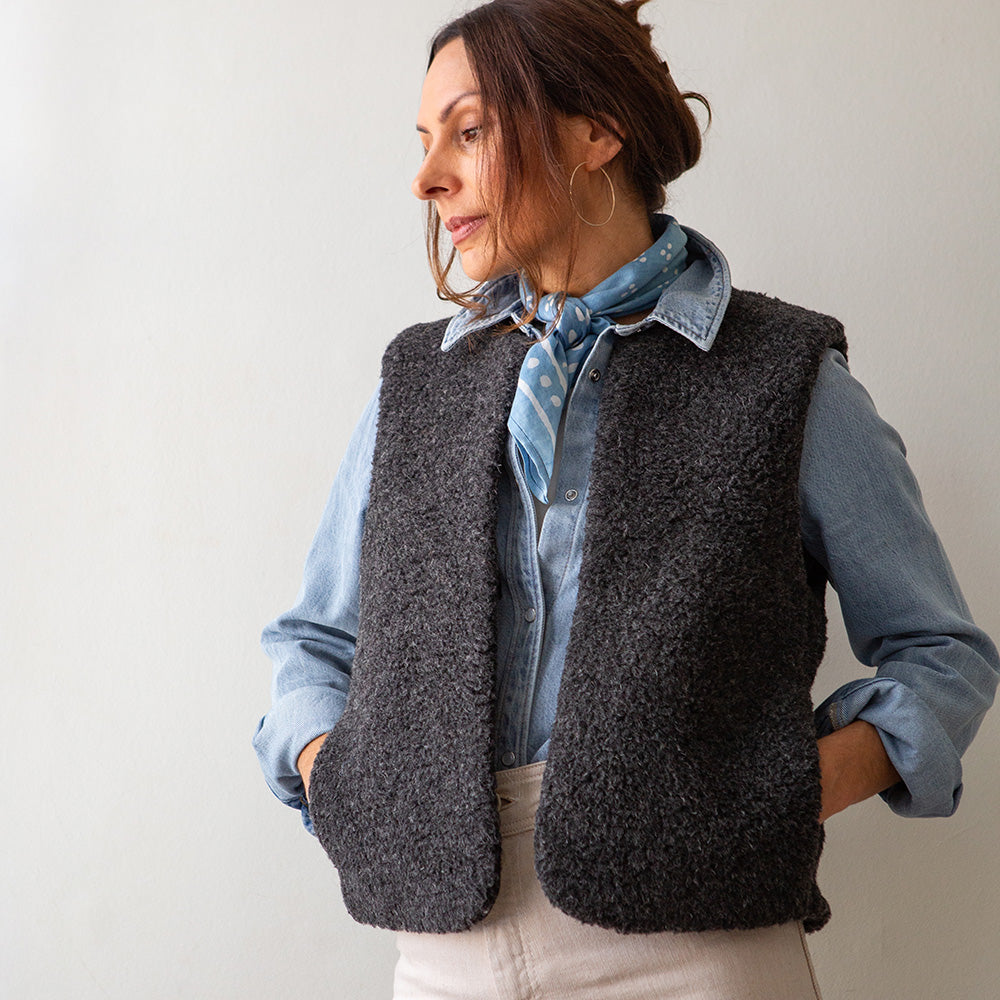 woman wearing a charcoal grey merino vest over a light wash denim shirt