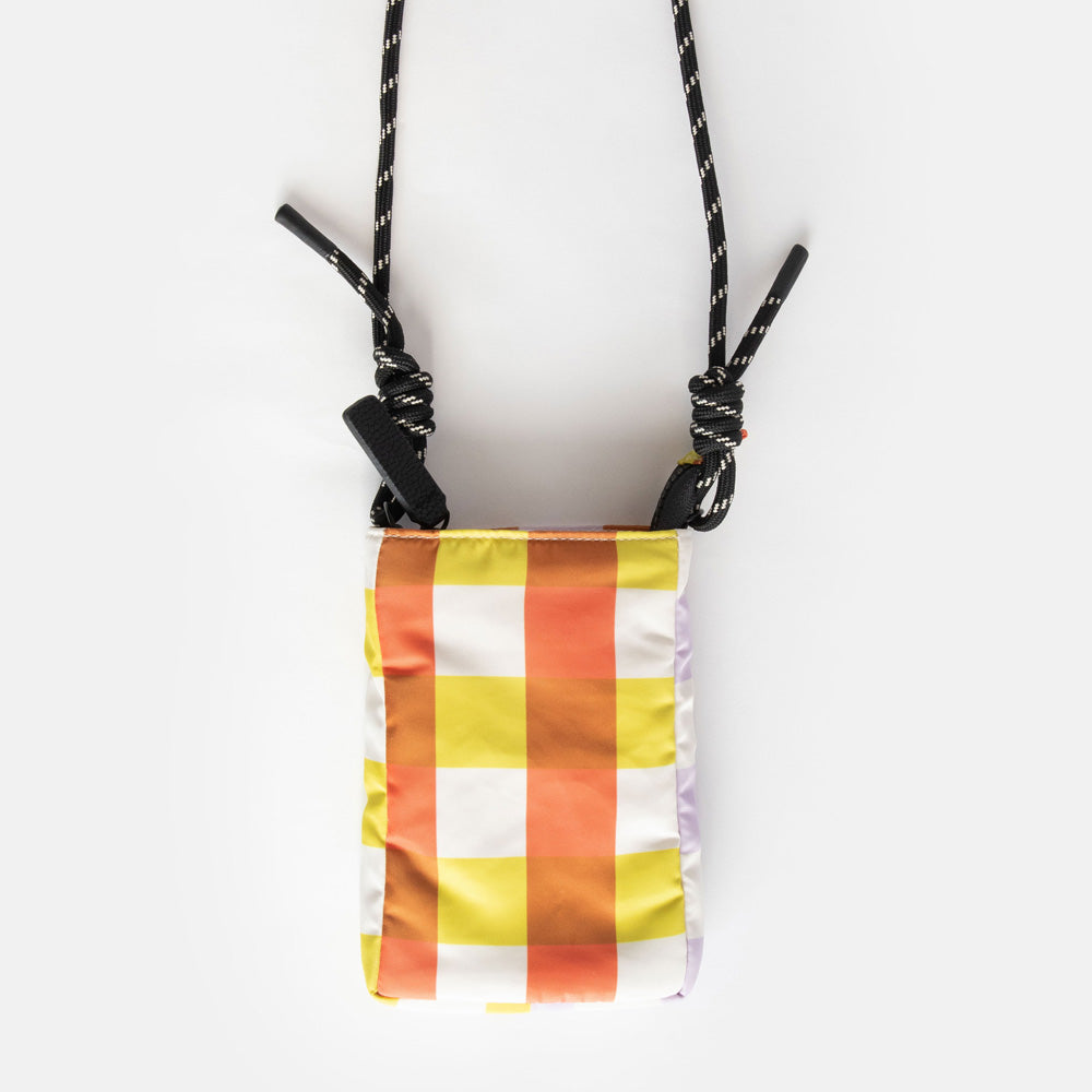 nylon padded phone bag in warm tones check design, with a monochrome adjustable cord strap and black zip pull