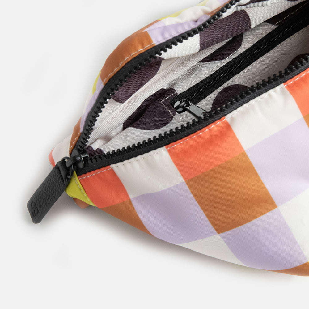 close up of colourful check crossbody bag showing the white with black spots internal lining and zip pocket