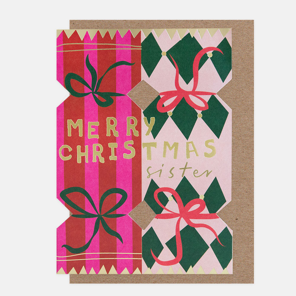 A Christmas greeting card with a kraft paper envelope, featuring die cut Christmas crackers in red and pink stripes, green and light pink diamond patterns, and gold foil text reading 'MERRY CHRISTMAS sister'.
