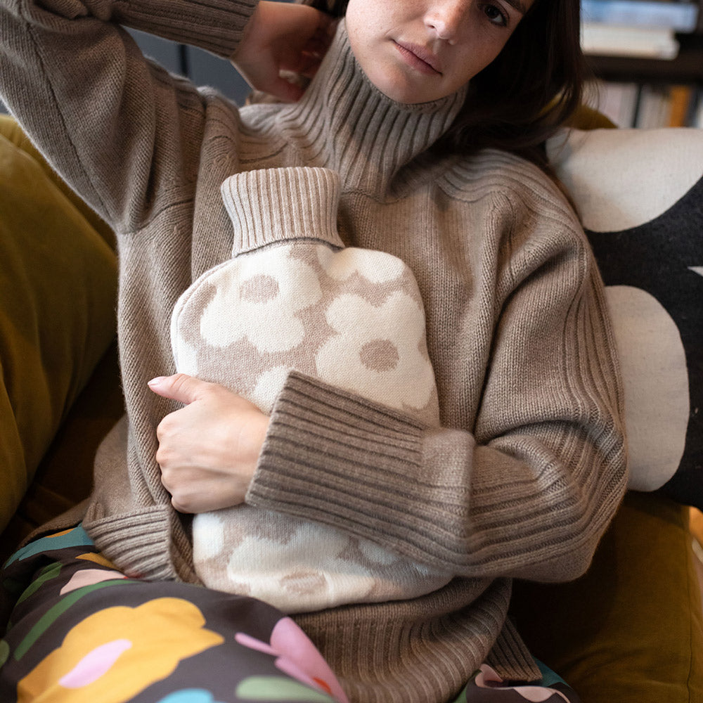 woman holding a hot water bottle with a taupe and white flower design