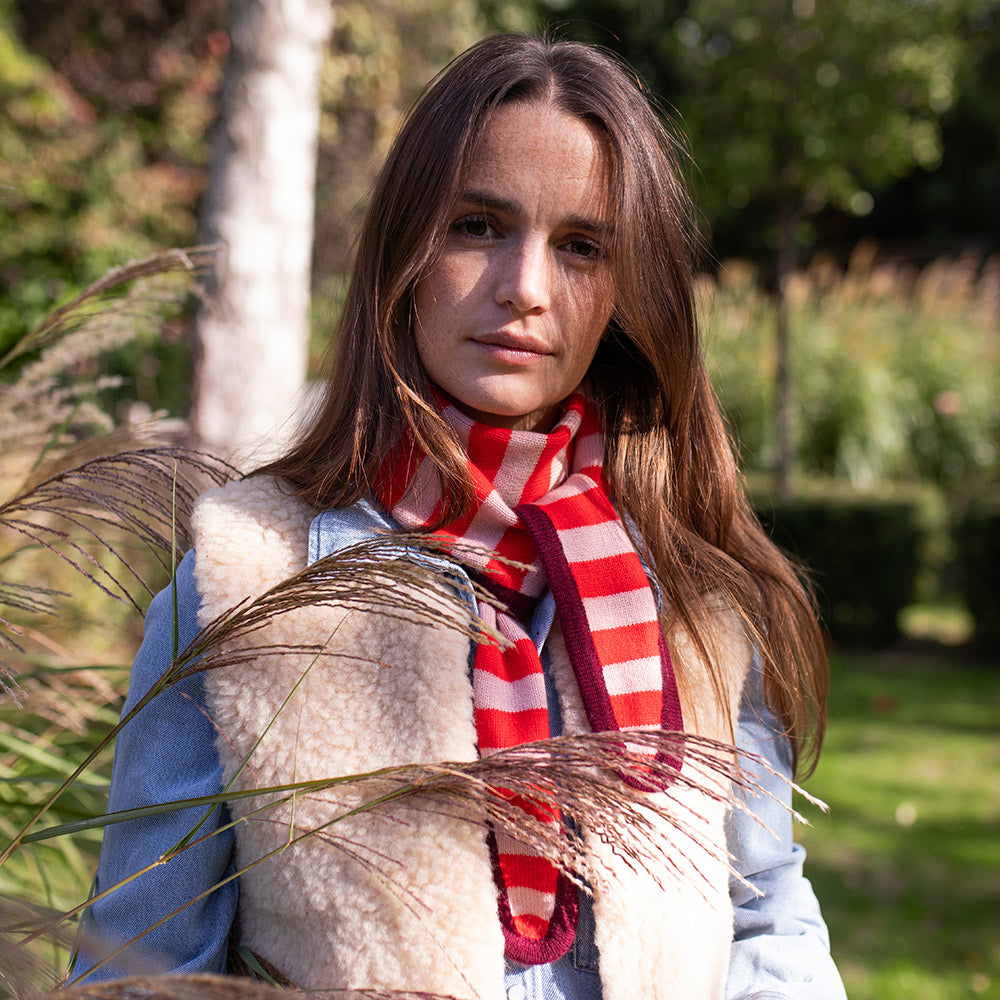 woman wearing a sheepskin gilet over a denim shirt with a red and pink stripe scarf