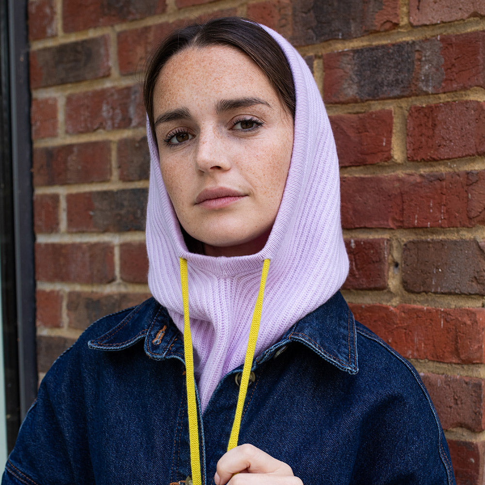 woman wearing a dark denim jacket with a lilac balaclava hood with yellow drawstrings
