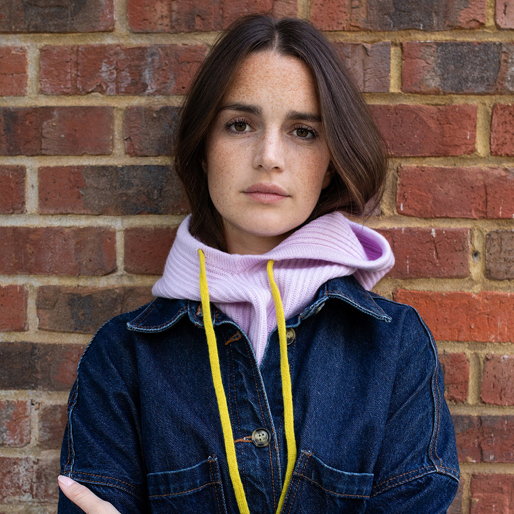 woman wearing a dark denim jacket with a lilac balaclava hood with yellow drawstrings
