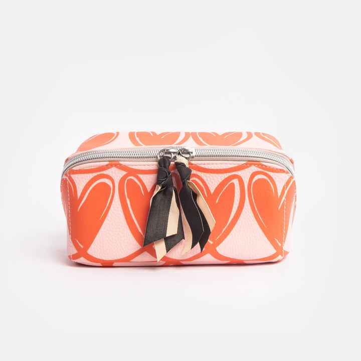 diagonal zip flat lay cosmetics bag with orange looped hearts design on pink base with black and white fabric zip pulls