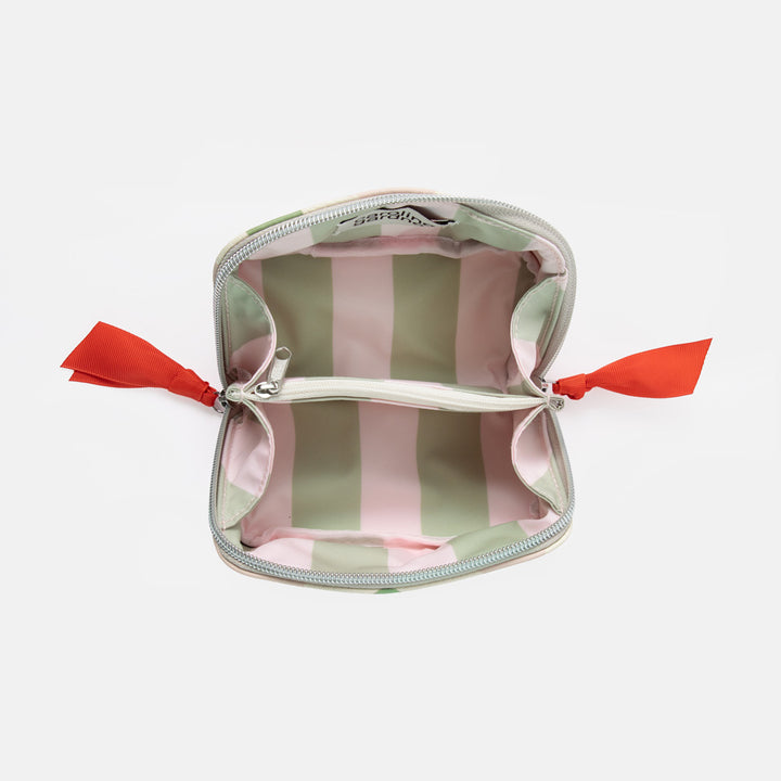 An open zippered cosmetic pouch with a pastel green and pink striped interior, silver zipper trim, and bright red ribbon ties on both sides, shown on a light gray background.