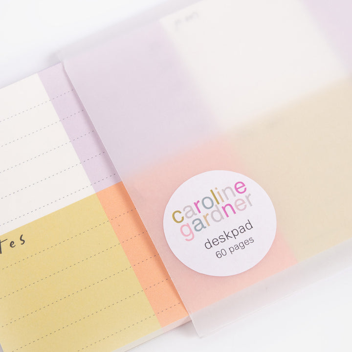 Colorful desk pad with 'caroline gardner' label on a white background
