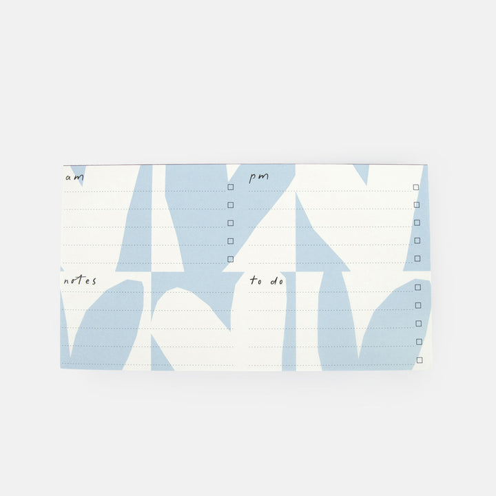A desk pad with a light blue and white abstract geometric pattern, featuring columns for morning and evening notes with checkboxes on the right side.
