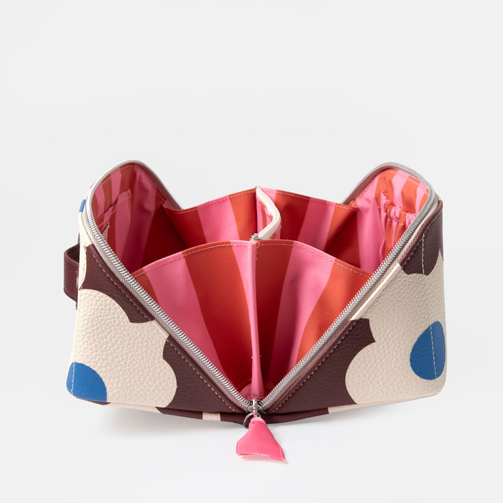 A rectangular zippered cosmetic bag with a cream background and a bold dark brown and blue floral pattern, featuring a pink & orange internal lining. 