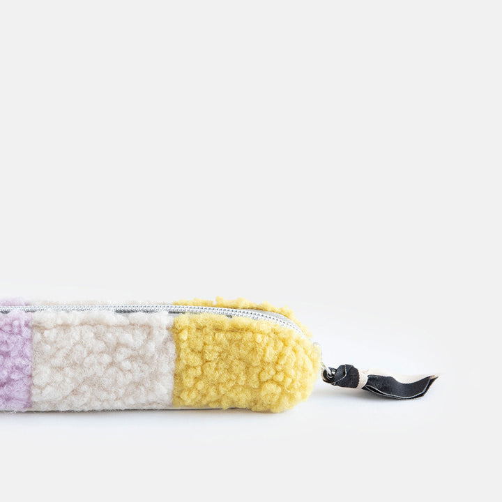 synthetic borg slim pencil case in cream, yellow and lilac with a black and white zip pull and big spots lining