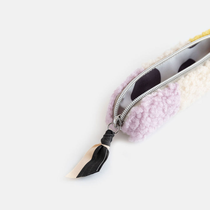 synthetic borg slim pencil case in cream, yellow and lilac with a black and white zip pull and big spots lining