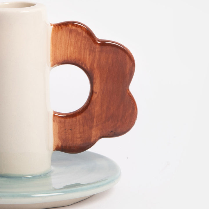 ceramic candle holder with light blue base and brown flower shaped loop handle