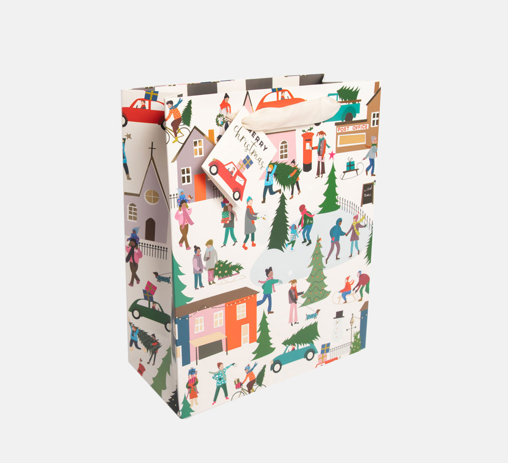 Christmas gift bag featuring a design of a snowy winter town scene, with a matching gift tag and fabric handles