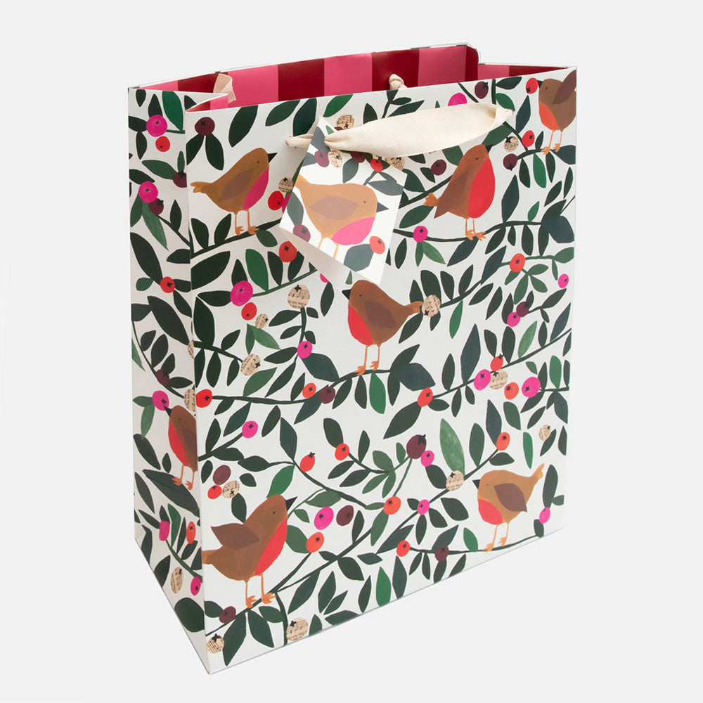 A white gift bag with a festive bird and berry pattern, featuring red striped handles and cream paper handles, shown on a light gray background.