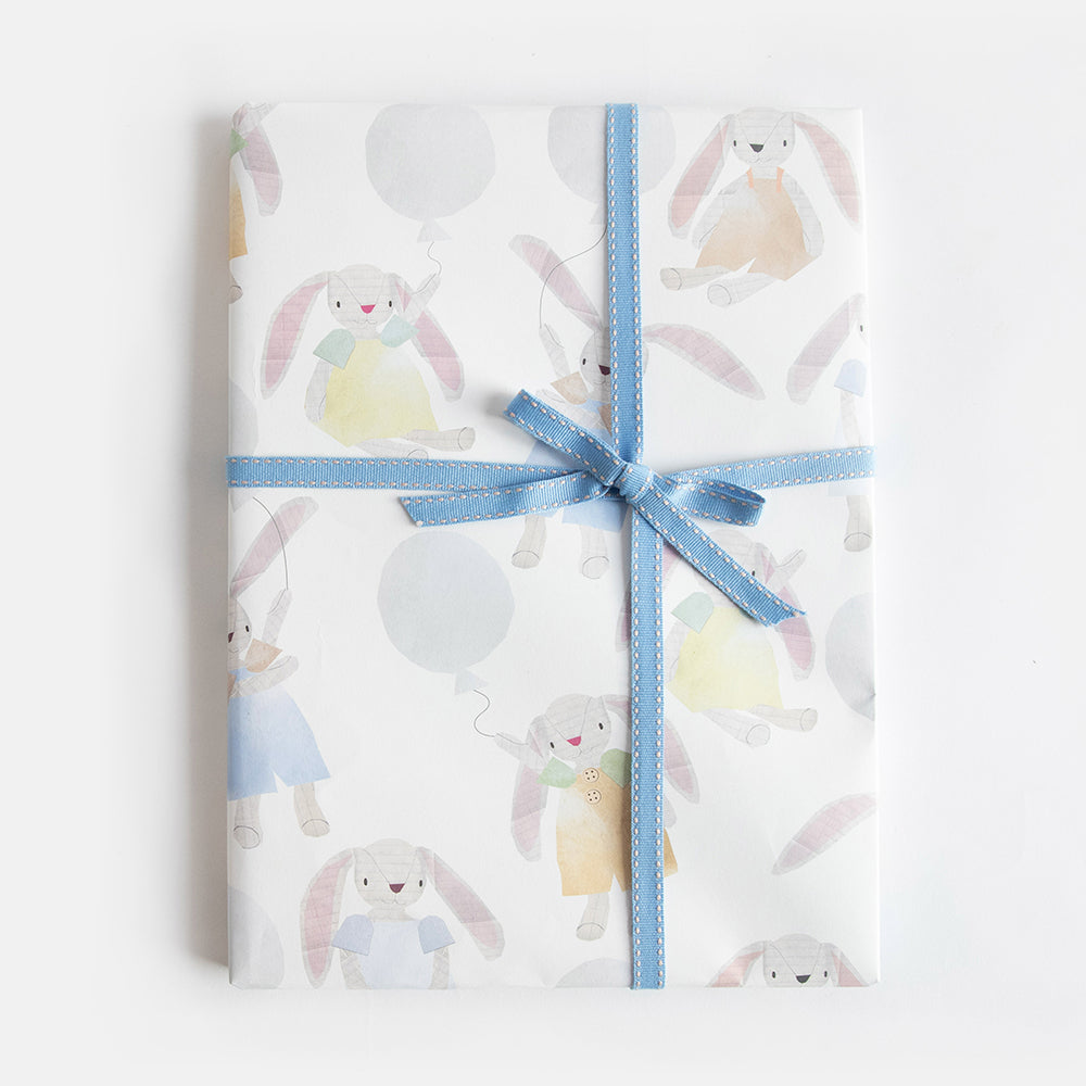 kids wrapping paper sheet featuring a design of hand drawn rabbit toys holding balloons. 